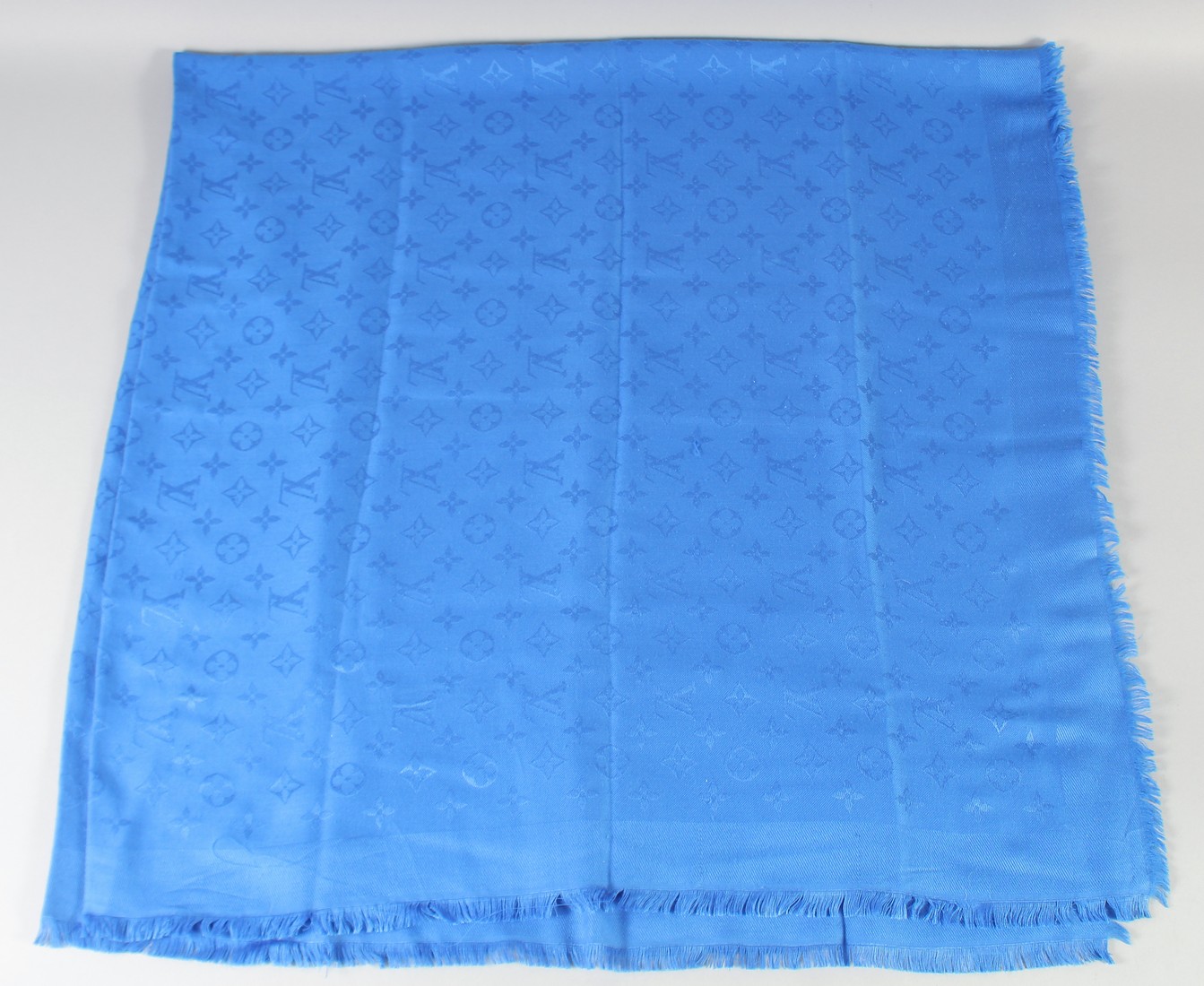 A LOUIS VUITTON BLUE SHAWL with Louis Vuitton emblems. 140cm x 120cm.