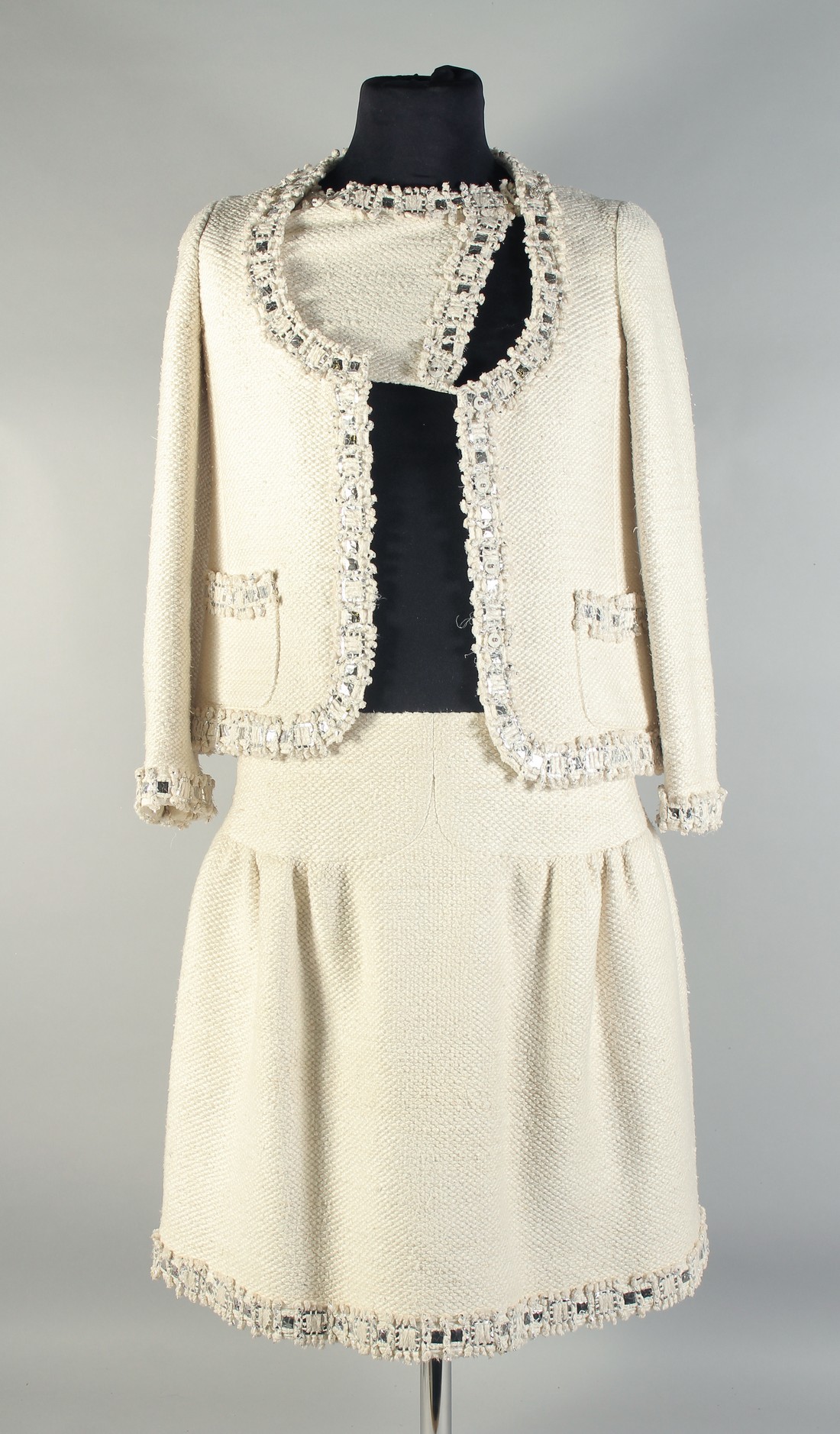 A CHANEL TWO PIECE CREAM SILK LADIES SUIT WITH METAL TRIM. Size 40.