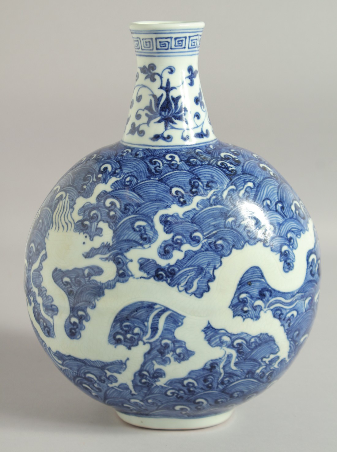 A CHINESE BLUE AND WHITE PORCELAIN MOON FLASK VASE, with incised white dragon on stylised waves,