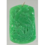 A GOLD RING ON A CARVED JADE PENDANT. 2.5ins x 1.5ins.