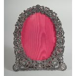 A VICTORIAN PIERCED SILVER EASEL PHOTOGRAPH FRAME with scrolls and flowers. 7ins x 5.5ins.
