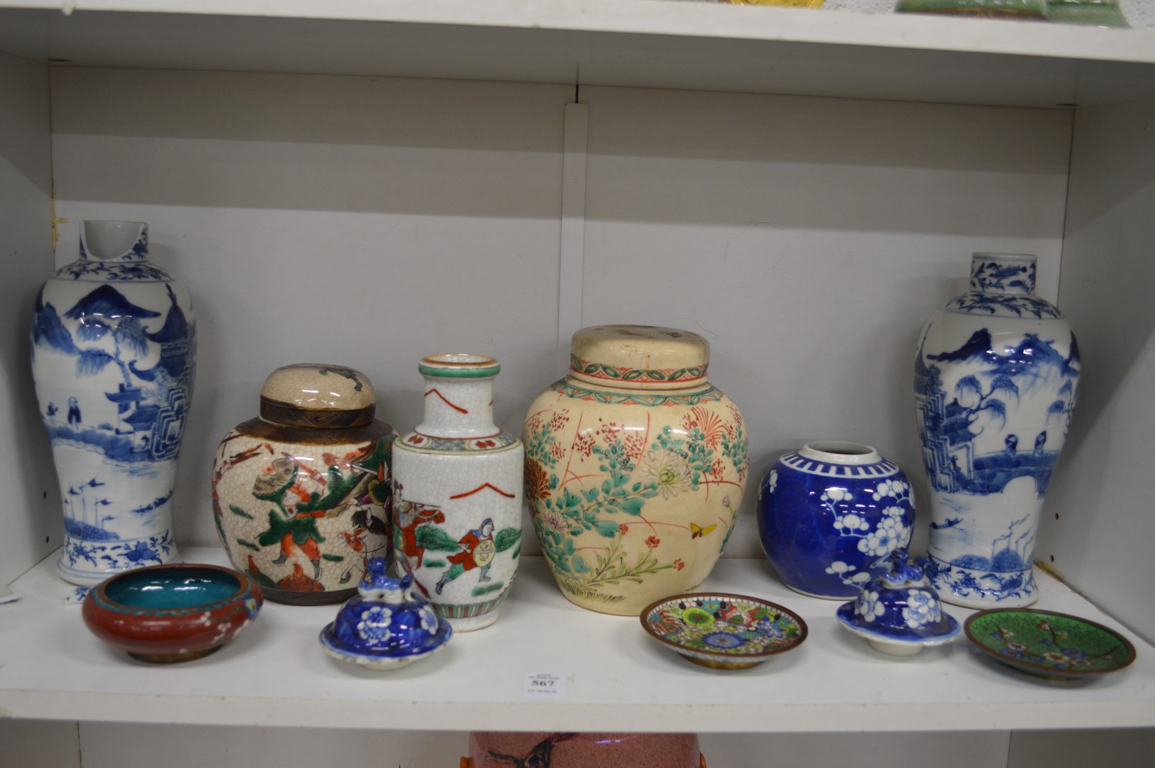 A shelf of Oriental porcelain and cloisonne items.