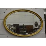 A gilt framed oval wall mirror.