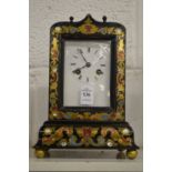 An ebonised mantle clock with brass inlaid decoration.
