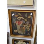 A silk thread and felt picture of a bird with basket of fruit in decorative gilt frame.