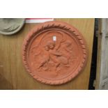 A large circular terracotta wall plaque moulded with cherubs.