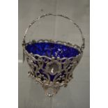A good silver pierced swing handle basket with blue glass liner.