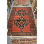 A Persian design rug, red ground with two large central medallions 158cm x 128cm.