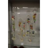 A collection of colourful glass barometers/thermometers.