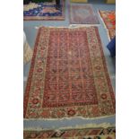 A Persian carpet, red ground with stylised decoration, worn and damaged 185cm x 130cm.