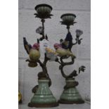 A pair of decorative pottery and brass candlesticks modelled as birds on branches.