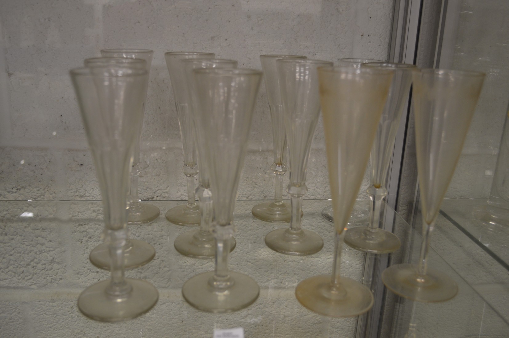 A set of ten cut glass champagne flutes together with a pair of etched champagne flutes.