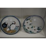 A Highland stoneware plaque painted with puffins together with a similar plate and two Sarah Akin-