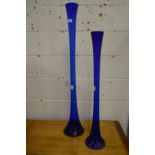 Two tall blue glass vases.