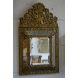 A decorative Continental embossed brass framed overmantle or hall mirror.