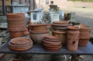 A quantity of terracotta plant pots with stands.
