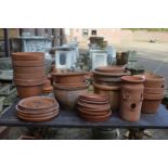 A quantity of terracotta plant pots with stands.