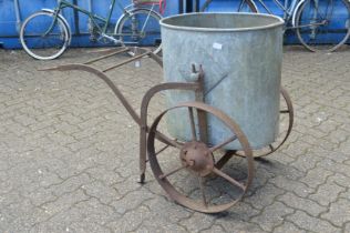 An old wrought iron and galvanised wheeled water butt.