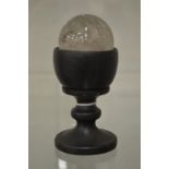 A crystal ball on turned wood stand.