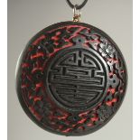 A CHINESE BLACK CINNABAR LACQUER PENDANT, 5cm diameter.