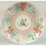 A CHINESE CORAL RED AND GREEN PORCELAIN PLATE, painted with panels of birds and flora, 26.5cm