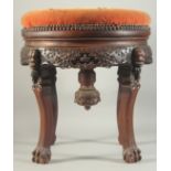 A LARGE CHINESE HARDWOOD STOOL, with upholstered seat, the skirt with relief faces, supported on