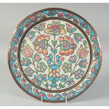 AN OTTOMAN ENAMELLED COPPER PLATE, with central floral spray and foliate border, 33.5cm diameter.