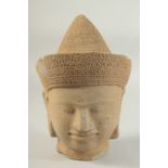 A FINELY CARVED STONE CAMBODIAN KHMER STYLE DEITY HEAD, 27cm high.