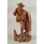 A CHINESE CARVED WOOD FIGURE OF A FISHERMAN, 26cm high.