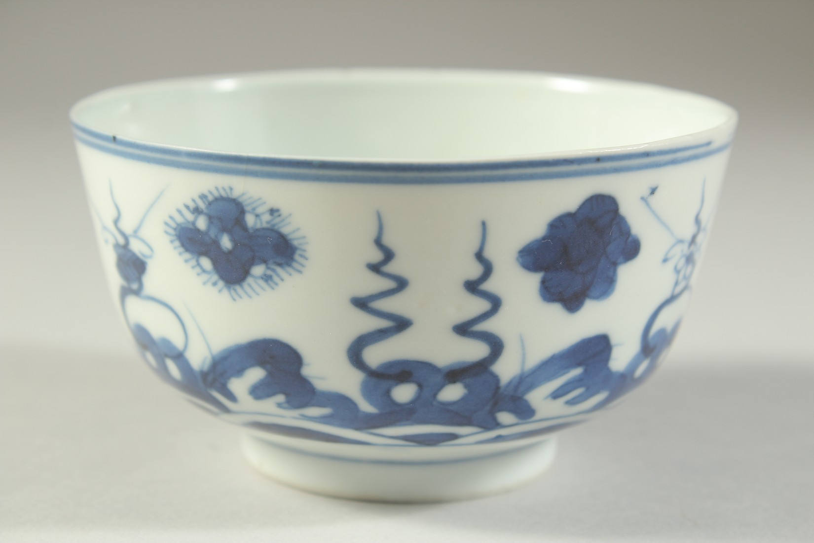 A SMALL 19TH CENTURY CHINESE BLUE AND WHITE PORCELAIN BOWL, painted with stylised waves and floral