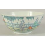 AN 19TH CENTURY CHINESE PORCELAIN BOWL, painted with various figures in an outdoor setting, the base