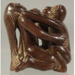 A CHINESE CARVED WOOD EROTIC NETSUKE. Signed.