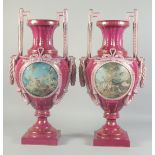 A LARGE PAIR OF BURGUNDY SEVRES STYLE TWO HANDLED URNS with circular classical scenes. 1ft 11ins