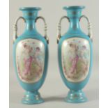 A PAIR OF BLUE SEVRES DESIGN TWO HANDLED VASES with panels of cupids.