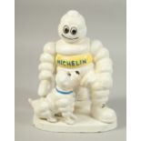 A WHITE CAST IRON MICHELIN MAN with a dog on a shaped base. 8ins high.