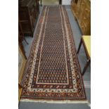 A PERSIAN RUNNER OR HALL CARPET, decorated with stylised Boteh design 450cm x 110cm.