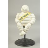 A WHITE CAST IRON MICHELIN MAN on a circular swivel base. 12ins high.