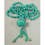 A STRING OF EIGHTY TURQUOISE BEADS AND PENDANT. 20ins long.