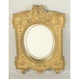 A GOOD GILDED BRONZE MIRROR with oval mirror, the case with bust and swags.