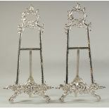 A PAIR OF SILVERED EASELS 19ins high.