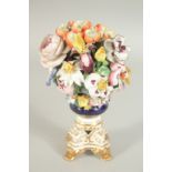 A GOOD DERBY FLOWER ENCRUSTED URN on a gilt base with claw feet. 7ins high.