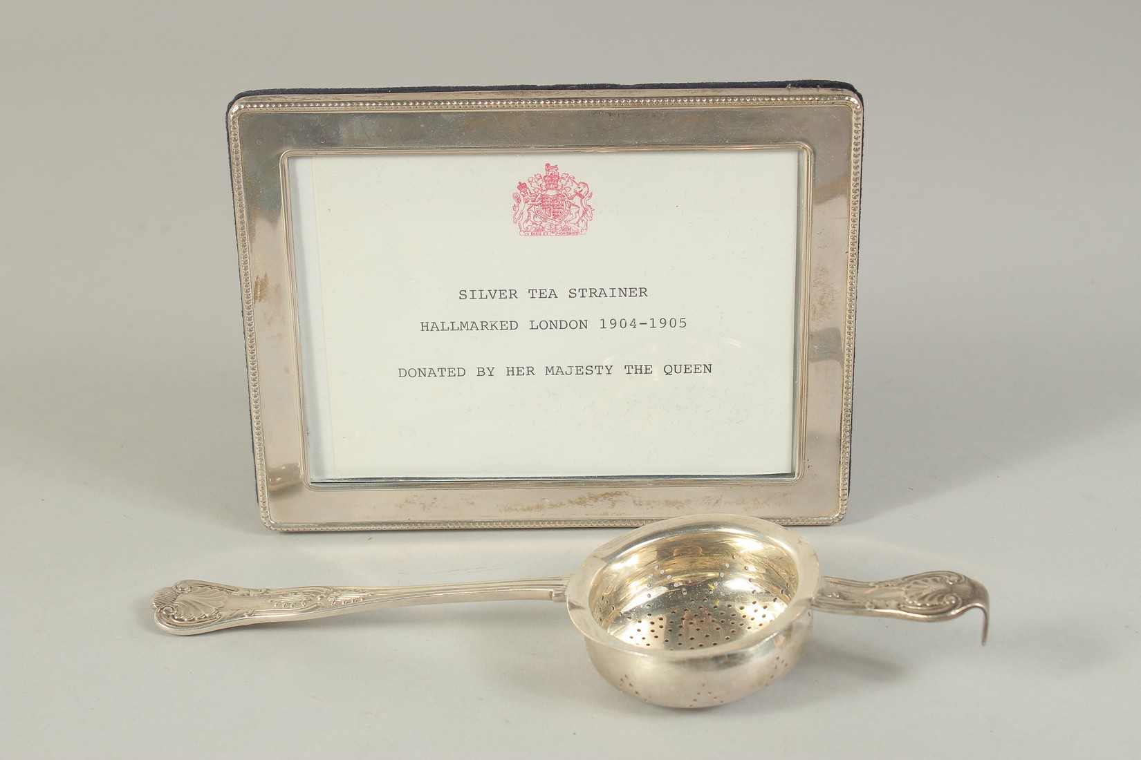 A SILVER TEA STRAINER, LONDON, 1904, together with a silver frame. Tea strainer: hallmarked.