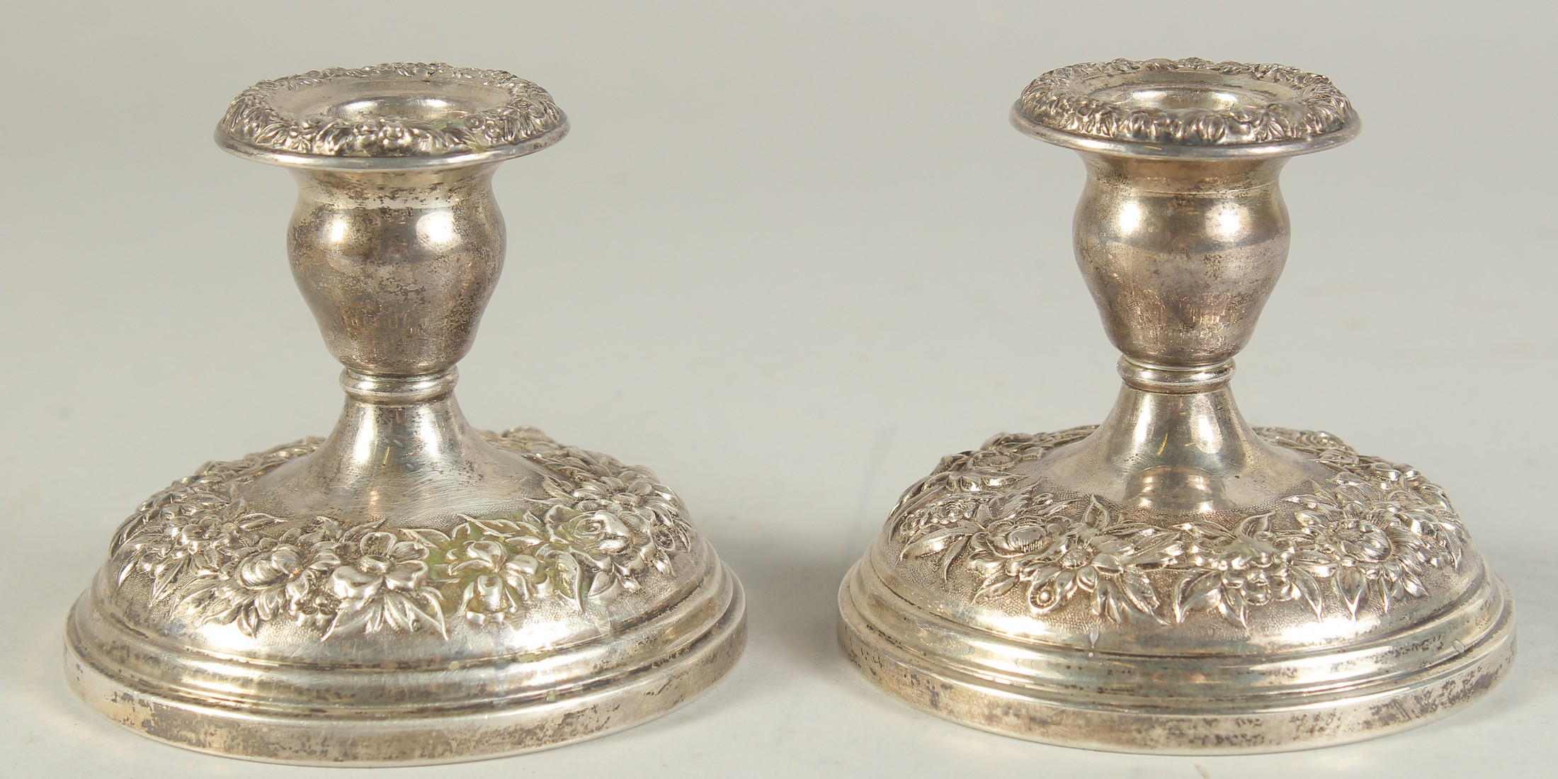 A PAIR OF SILVER EMBOSSED SQUARE CANDLESTICKS. 3.5ins high.