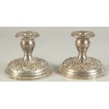 A PAIR OF SILVER EMBOSSED SQUARE CANDLESTICKS. 3.5ins high.