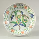 A CHINESE WUCAI PORCELAIN CHARGER painted with a bird and flora. 33.5cm diameter.