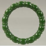 A CHINESE CARVED GREEN JADE BANGLE. 2.75ins