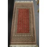A SMALL MODERN PERSIAN DESIGN RUG, red ground with stylised decoration. 144cm x 66cm.