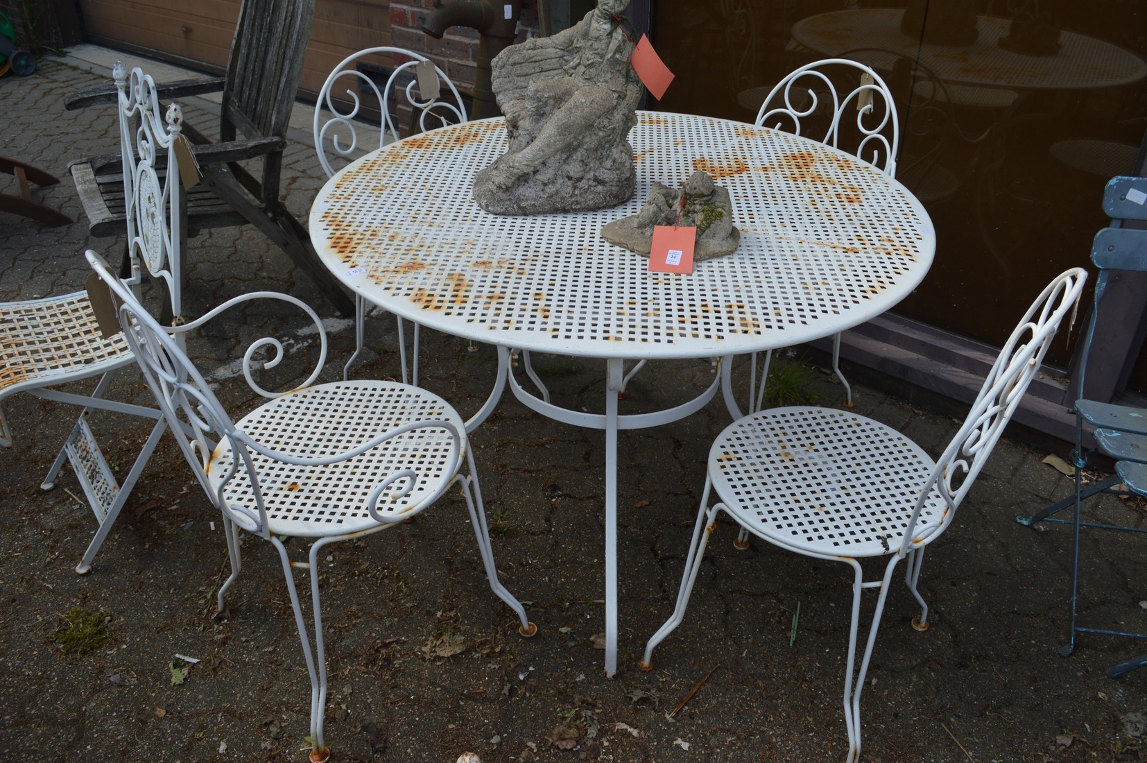 A white painted wrought iron circular garden table and four similar chairs, two with arms.