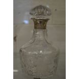 A cut glass decanter with silver collar.