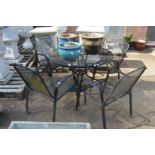 A circular black painted metal patio table with four armchairs and a parasol base.
